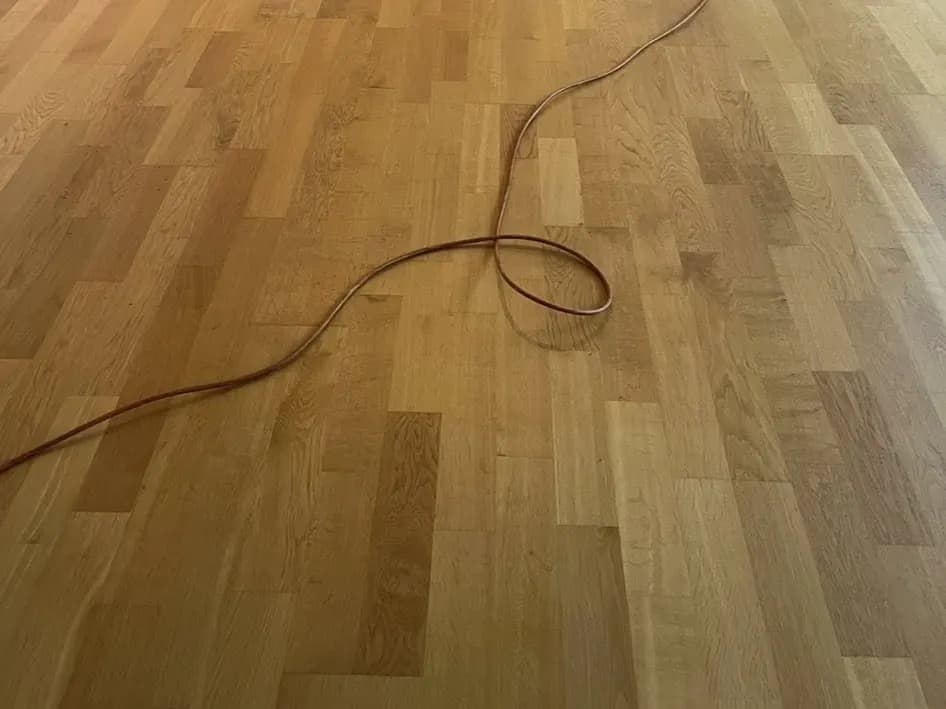 Trägolv i kök före slipning: synliga fläckar och matt, ojämn yta.