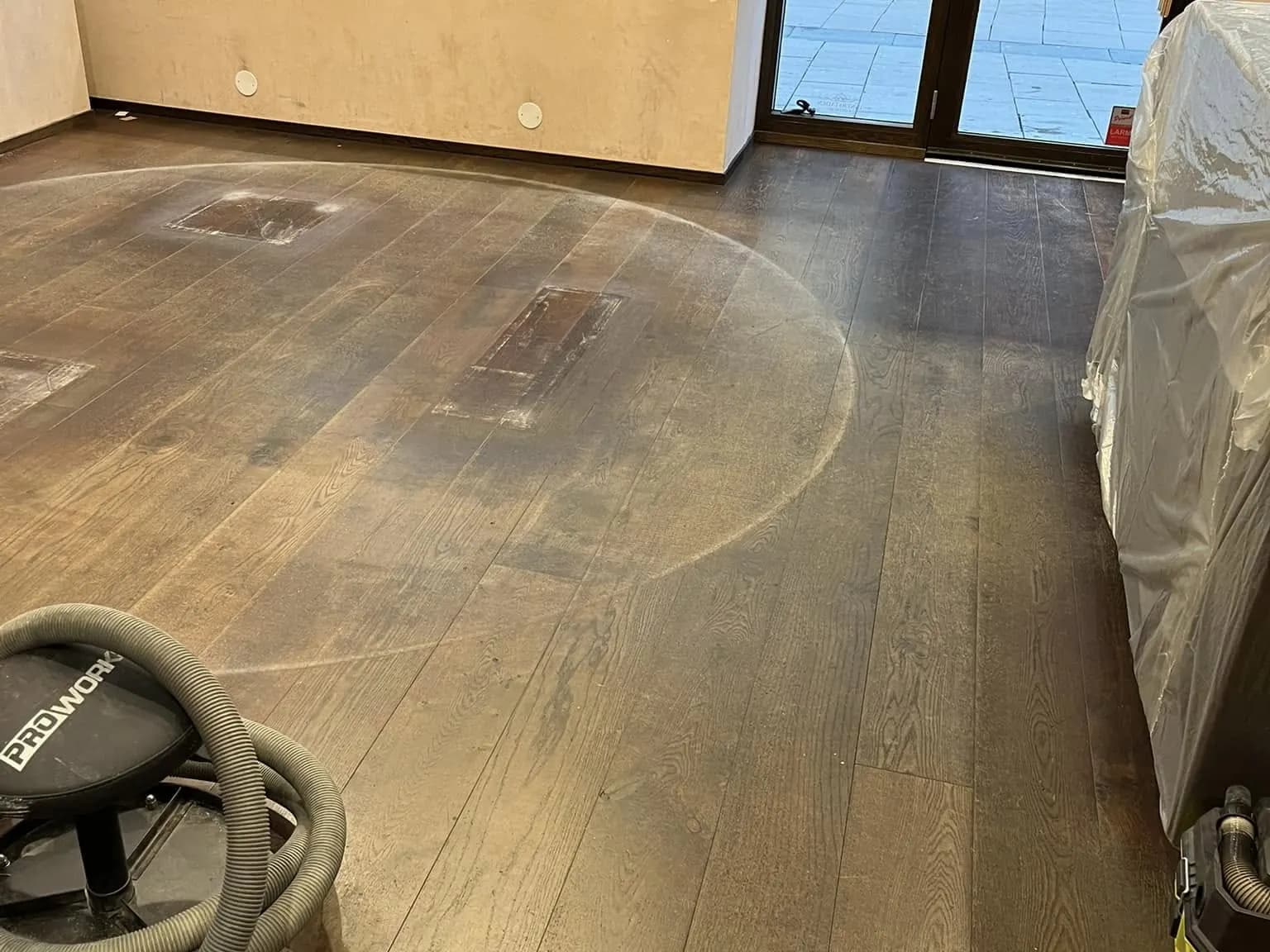 Slitet trägolv i butikslokal före slipning: repor och matt yta.