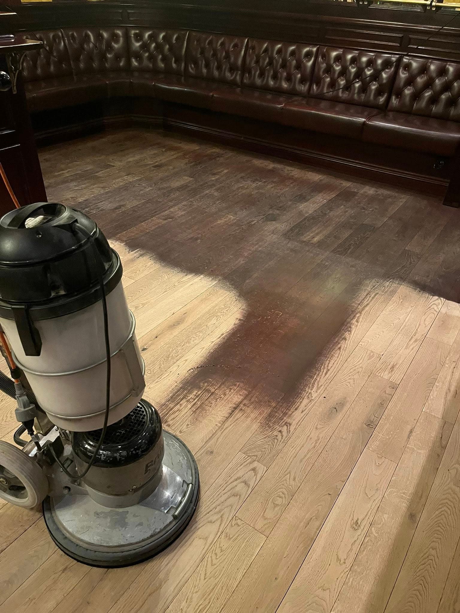 Slitet trägolv i restaurangmiljö före renovering: märken och ojämn finish.