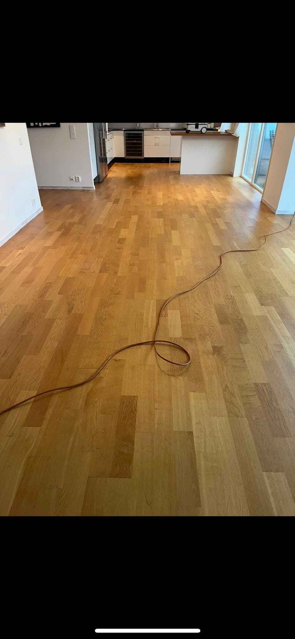 Trägolv i kök före slipning: synliga fläckar och matt, ojämn yta.