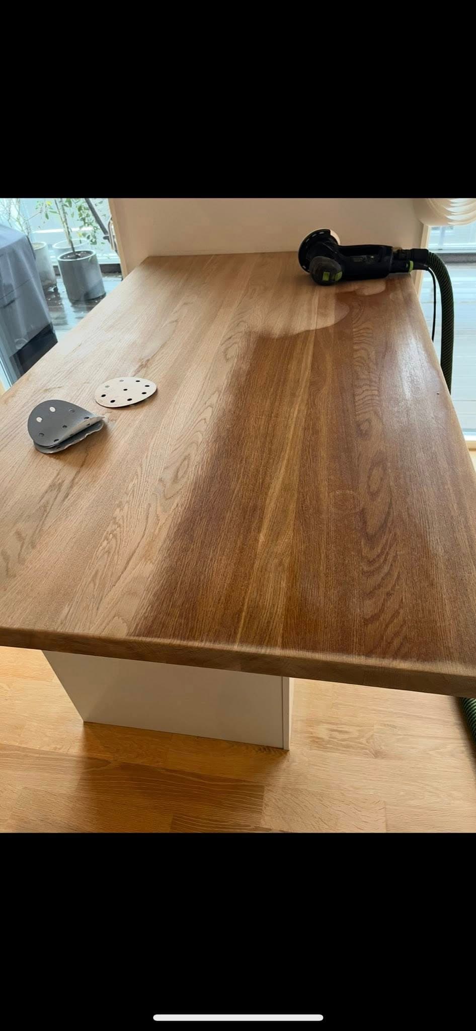 Träbänkskiva i kök före slipning: synligt slitage och ojämn ton vid arbetsyta.