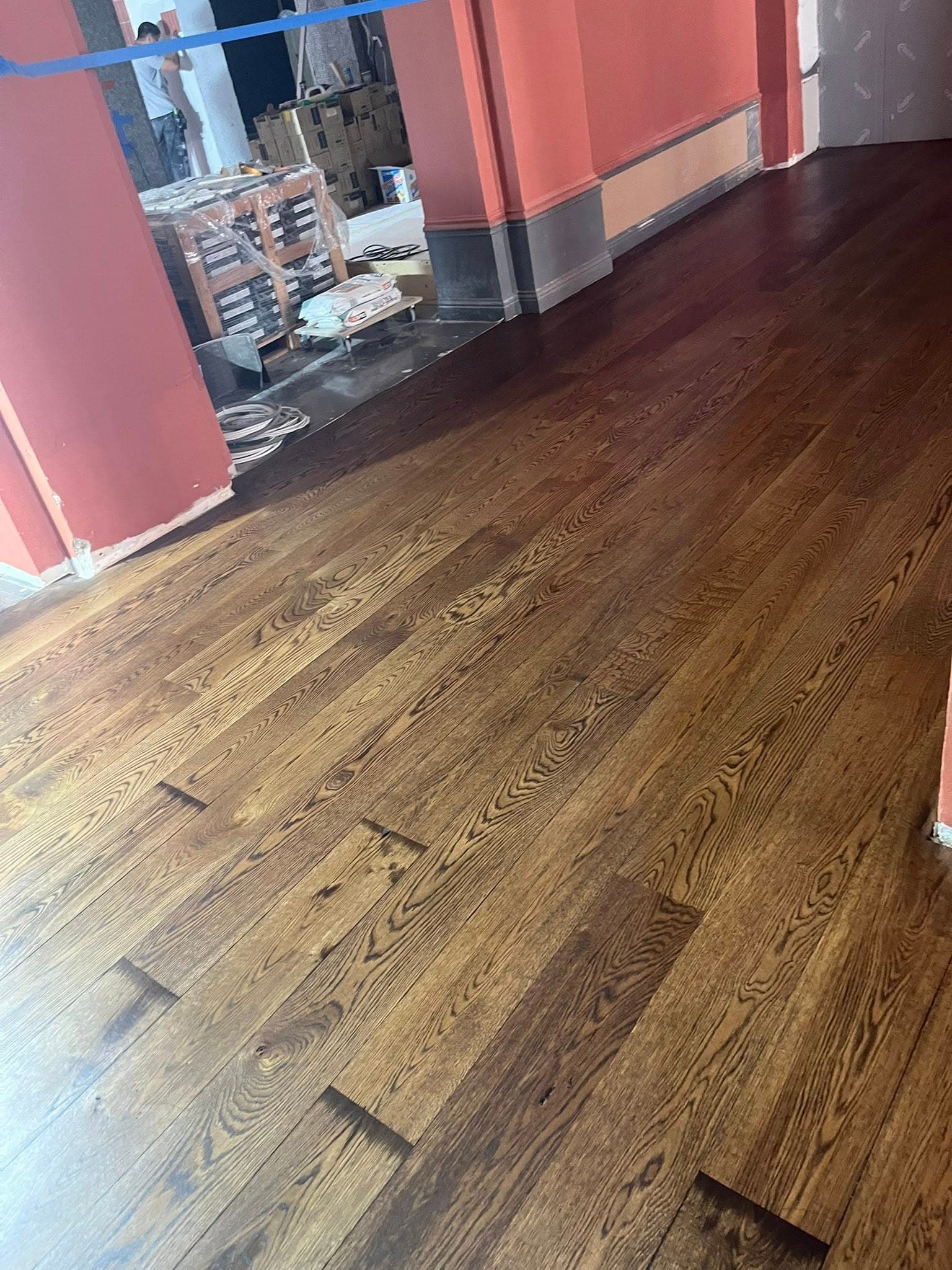 Trägolv med mörk, ojämn ton före slipning i bostad i Göteborg.