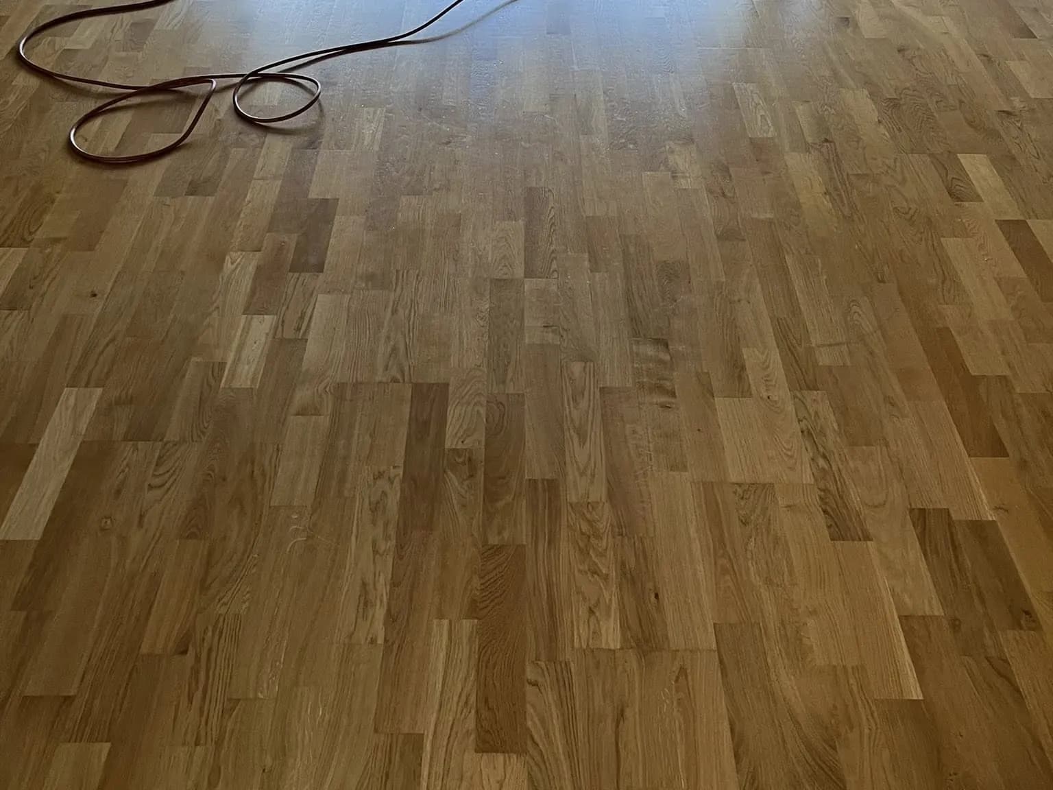 Parkett eller plankgolv före slipning: ojämn yta och fläckiga partier.